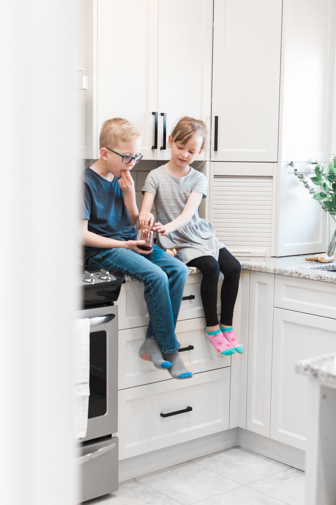 Photo of Drizzle Cacao Luxe Honey being enjoyed by two children sitting on a kitchen counter.