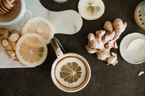 A top-down view of tea, lemon and ginger on a kitchen counter.