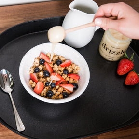Drizzle White Raw Honey being drizzled onto a smoothie bowl with strawberries.