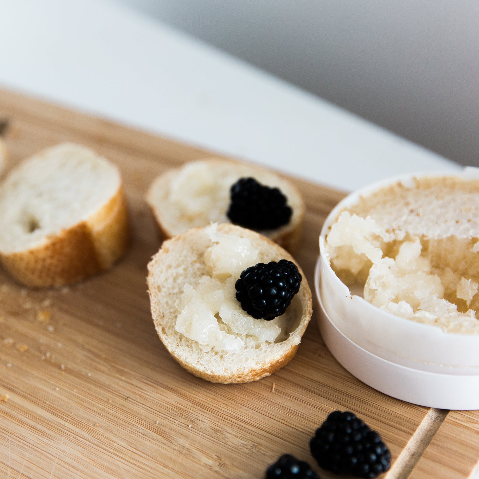 Drizzle Honeycomb next to bread and blackberries on a charcuterie board.