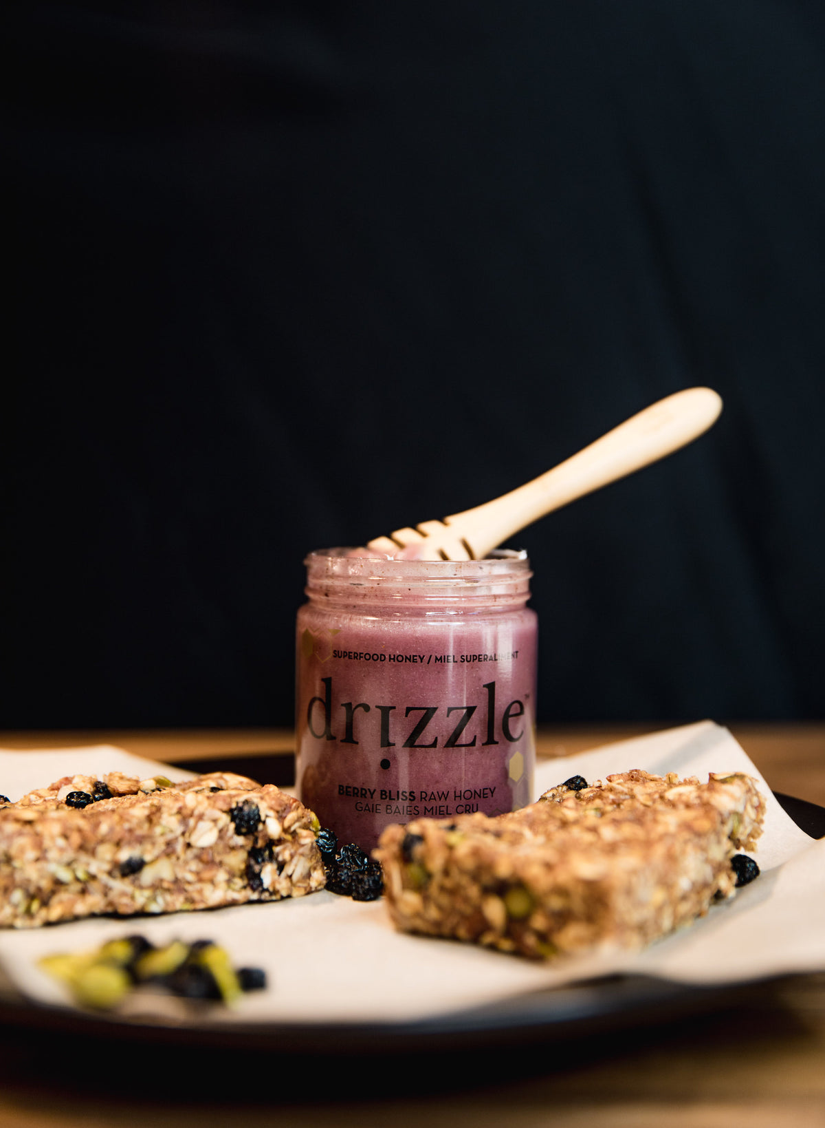 Photo of Drizzle Honey Berry Bliss sitting atop a cutting board next to homemade granola bars.