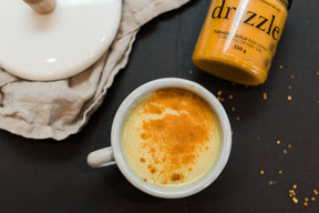 Drizzle Turmeric Gold Raw Honey next to a turmeric latte.